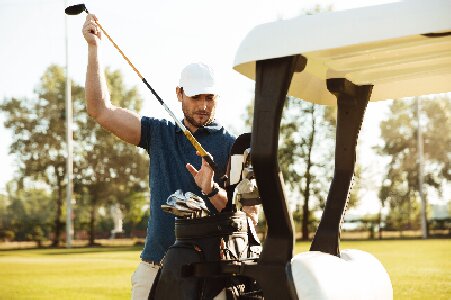 przystojny-golfista-bierze-kije-z-torby-wózka-golfowego przystojny-golfista-bierze-kije-z-torby-wózka-golfowego